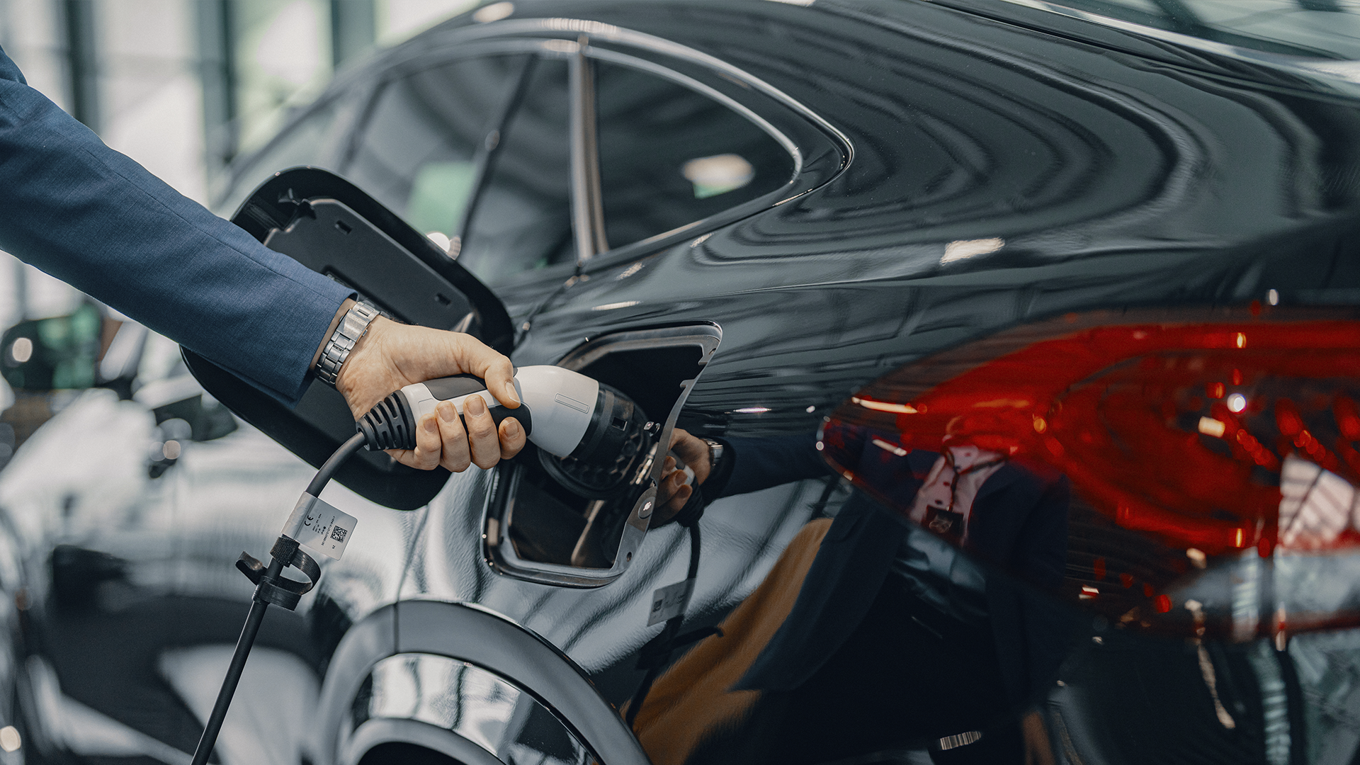 Henkilö laittaa autoa lataukseen