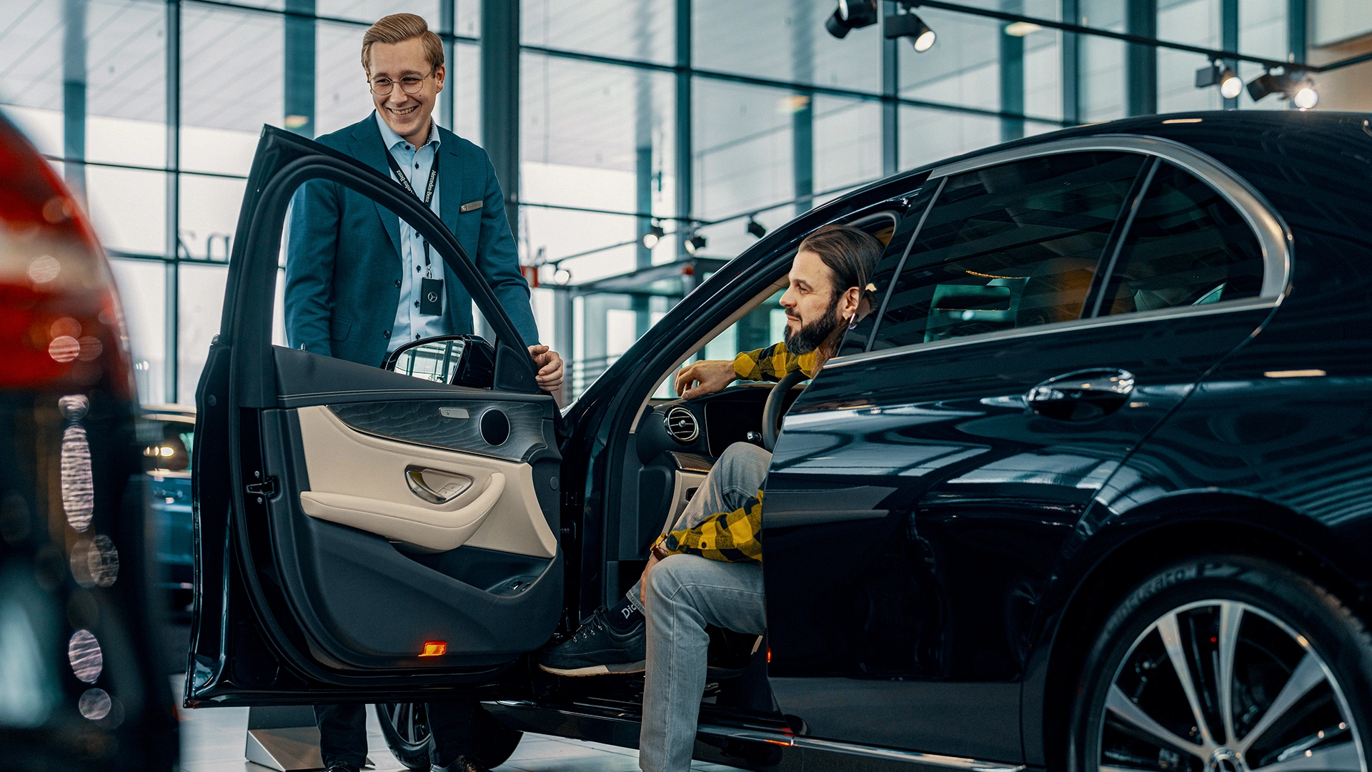 Asiakas ja automyyjä Mercedes-Benz henkilöautoa tutkimassa.