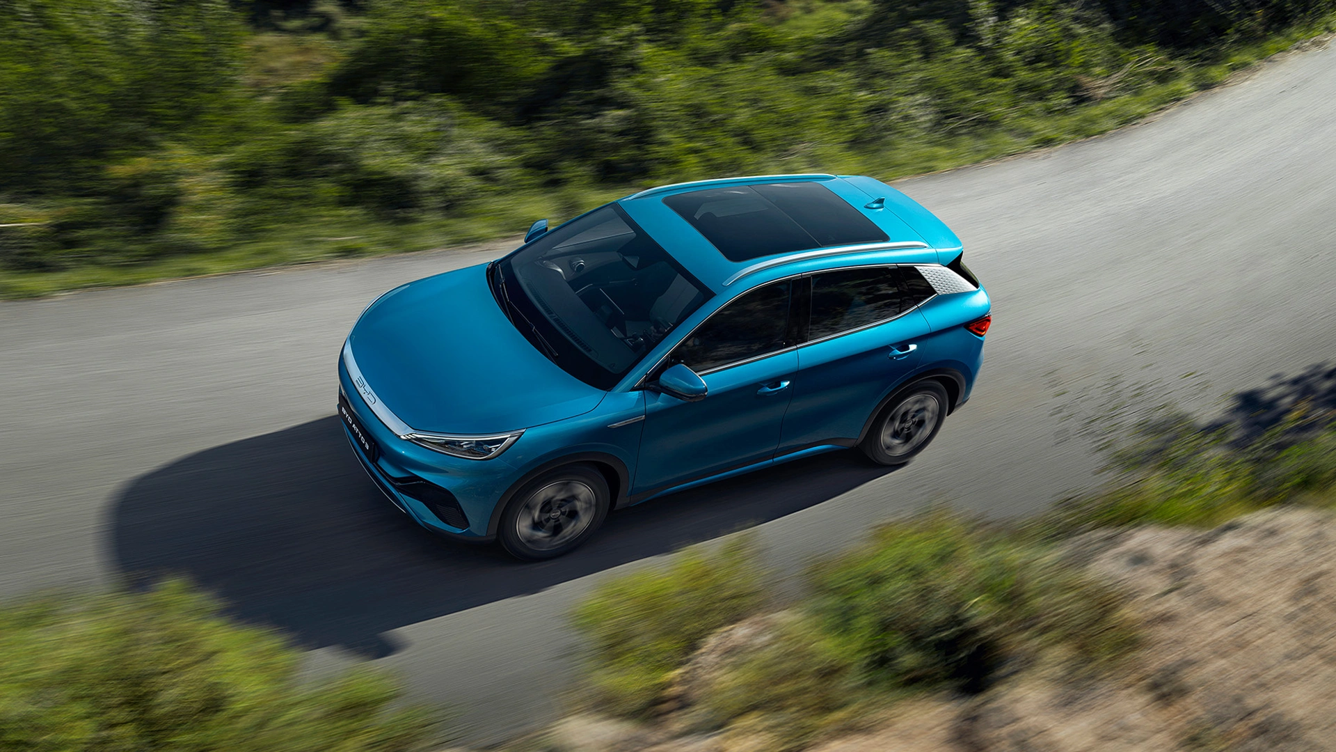 BYD Atto 3 täyssähköauto ajaa asfaltoidulla tiellä vehreässä maisemassa