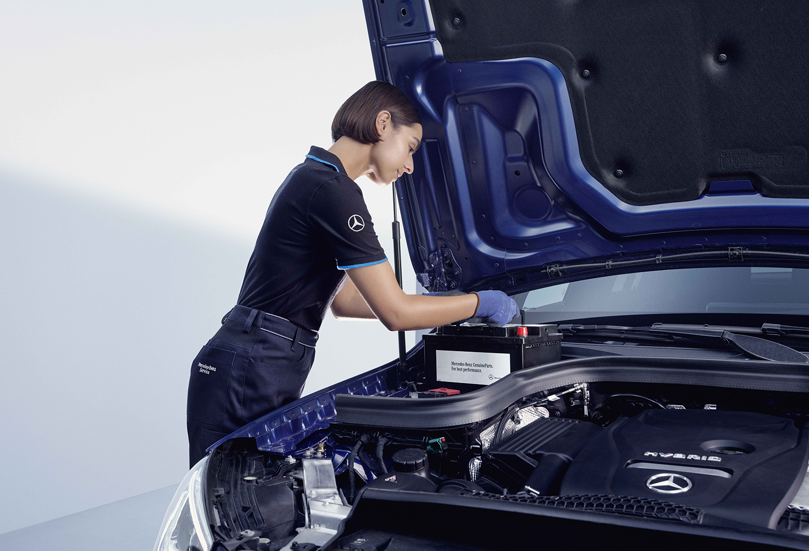 Mercedes-Benz-mekaanikko vaihtamassa Mercedeksen käynnistysakkua.